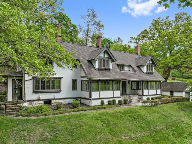back of house featuring a lawn, a chimney, and stucco siding