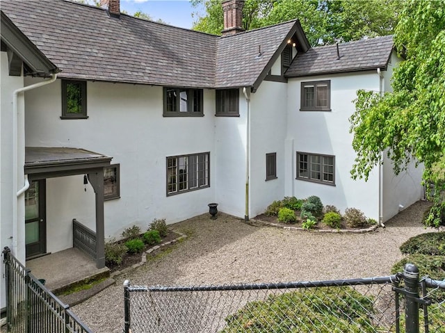 back of property with a chimney, stucco siding, a fenced backyard, and a high end roof