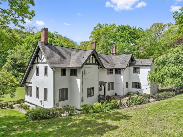 back of house featuring stucco siding and a chimney