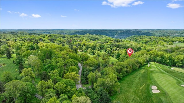 drone / aerial view of a heavily wooded area and a golf course