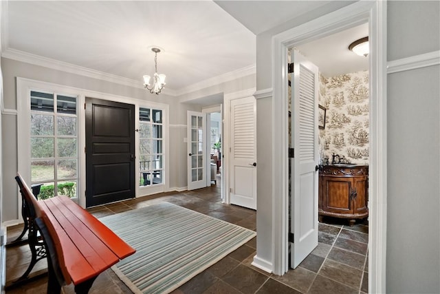 foyer entrance featuring a chandelier, stone tile flooring, crown molding, and baseboards
