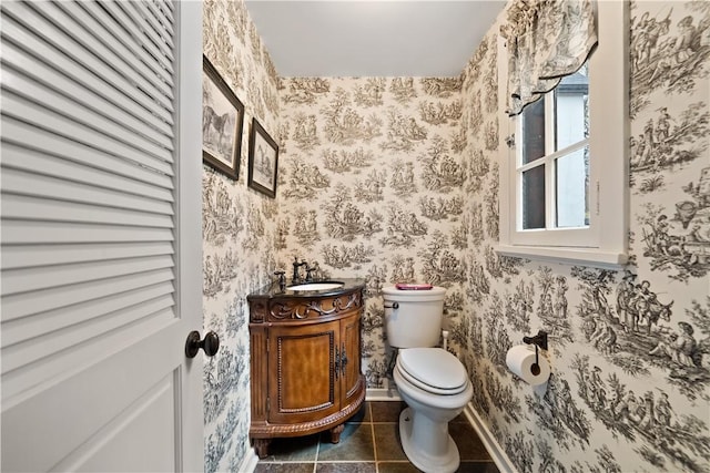 half bathroom with wallpapered walls, vanity, toilet, tile patterned floors, and baseboards