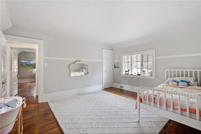 bedroom with vaulted ceiling, wood finished floors, and baseboards