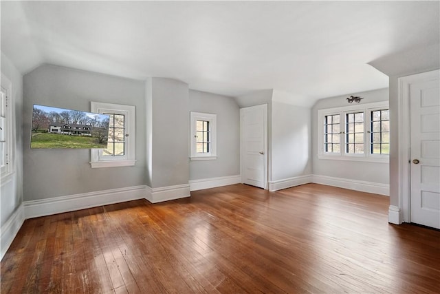 spare room featuring hardwood / wood-style flooring, vaulted ceiling, healthy amount of natural light, and baseboards