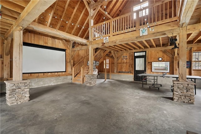 miscellaneous room featuring high vaulted ceiling, healthy amount of natural light, concrete flooring, and stairs