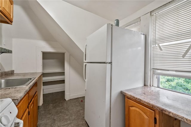 1608 Union Ave, Mckeesport, PA 15132 - kitchen with freestanding refrigerator, dark tile patterned flooring, stove, light countertops, and brown cabinetry