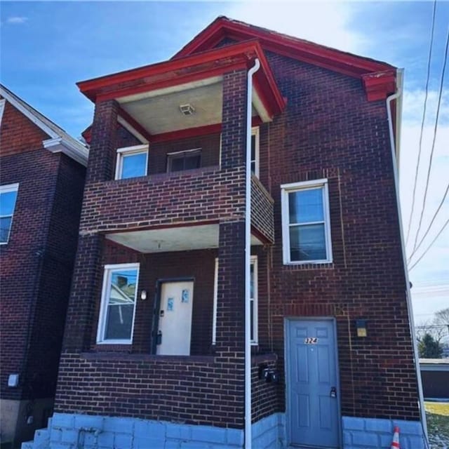 view of front facade featuring brick siding and a balcony