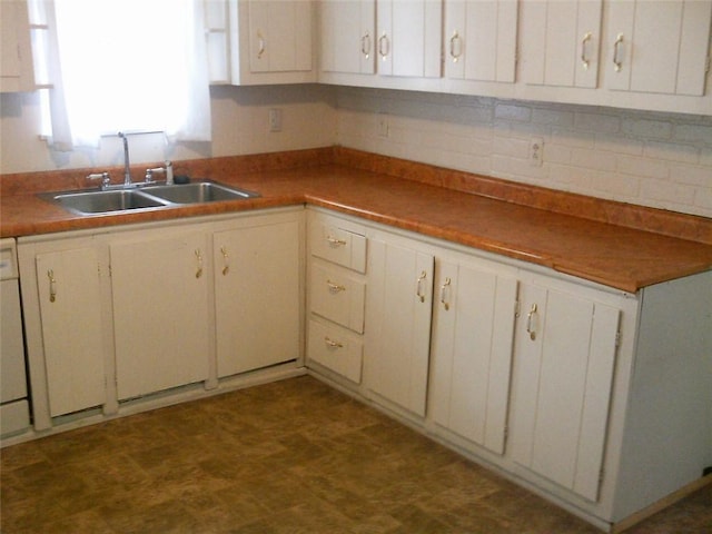 kitchen featuring a sink, dark floors, decorative backsplash, and white cabinetry