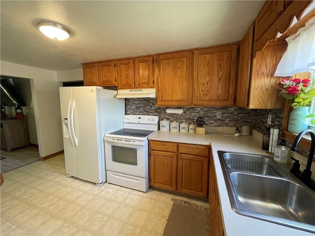 kitchen featuring white appliances, a sink, under cabinet range hood, brown cabinets, and light countertops