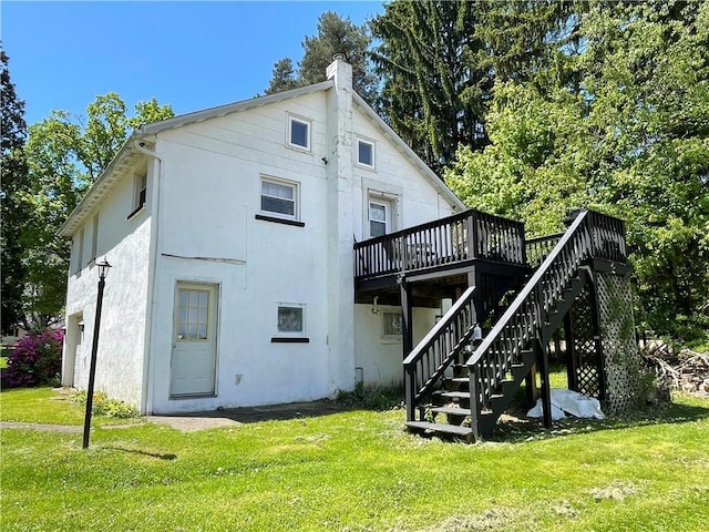 rear view of property with a deck, stucco siding, a yard, and a chimney
