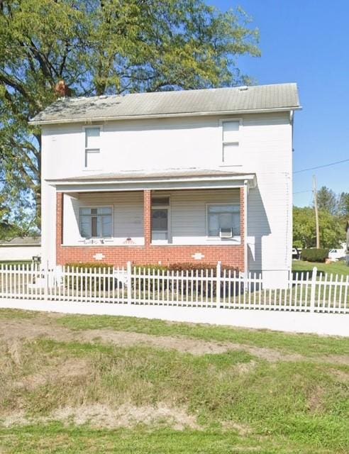 view of front facade featuring brick siding and a fenced front yard