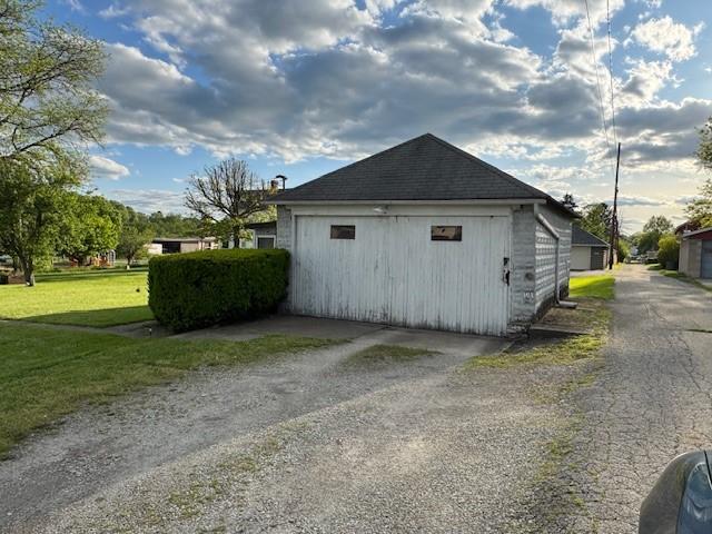 view of side of home with driveway, a lawn, and a garage