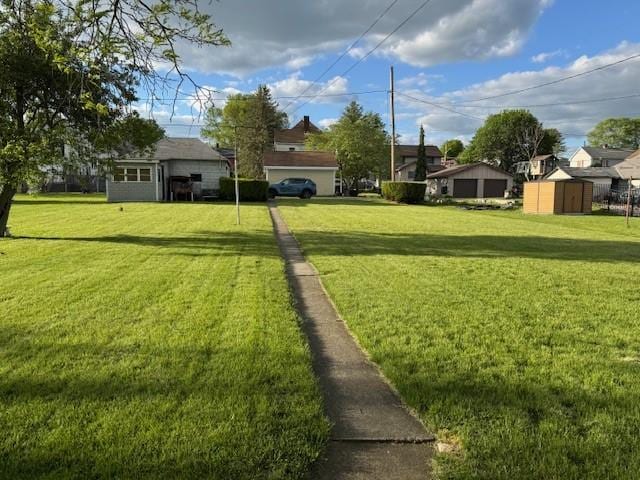 view of green lawn featuring a storage unit, an outbuilding, and a residential view