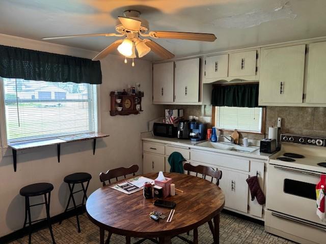 kitchen featuring white range with electric stovetop, tasteful backsplash, a ceiling fan, a sink, and black microwave