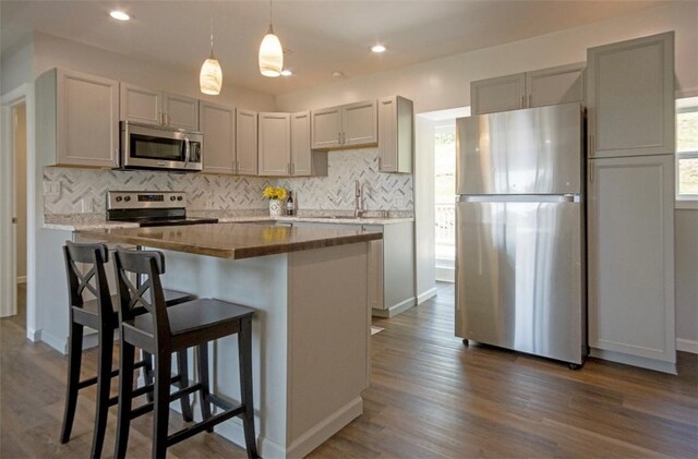 1435 Orchard St, New Sewickley Twp, PA 15042 - kitchen featuring appliances with stainless steel finishes, decorative backsplash, a kitchen island, dark wood finished floors, and recessed lighting