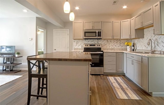 1435 Orchard St, New Sewickley Twp, PA 15042 - kitchen featuring appliances with stainless steel finishes, a sink, backsplash, dark wood-style floors, and a center island