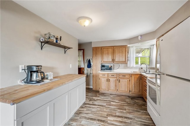 kitchen featuring white appliances, open shelves, light wood finished floors, a sink, and wooden counters