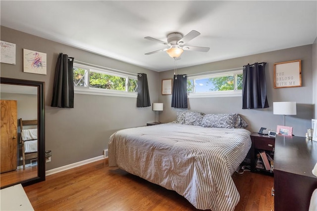 bedroom featuring multiple windows, wood finished floors, baseboards, and ceiling fan