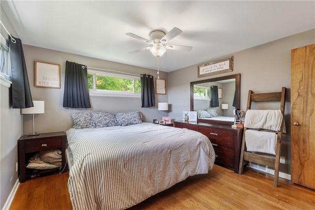 bedroom with light wood finished floors, baseboards, and a ceiling fan