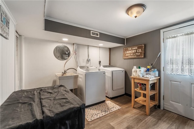 laundry room with crown molding, washer and clothes dryer, and wood finished floors