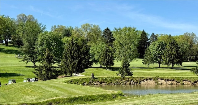 surrounding community featuring a water view, a yard, golf course view, and view of wooded area