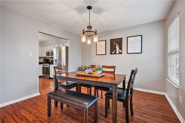 dining space featuring a chandelier, dark wood-type flooring, and baseboards