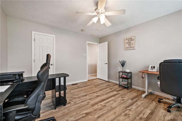 office area featuring ceiling fan, light wood-type flooring, and baseboards