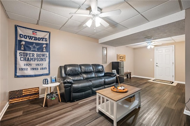 living area with ceiling fan, a paneled ceiling, baseboards, and dark wood-style floors