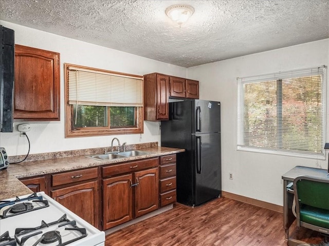 kitchen featuring freestanding refrigerator, a sink, dark wood-style flooring, a textured ceiling, and white gas stove