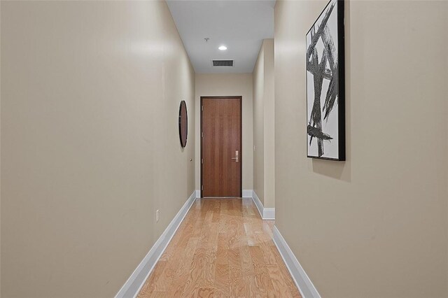 corridor with light wood-style flooring, baseboards, and recessed lighting