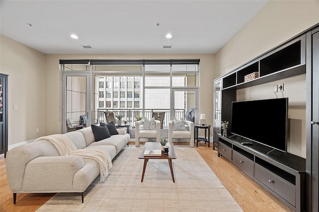living area with light wood-type flooring, recessed lighting, and baseboards