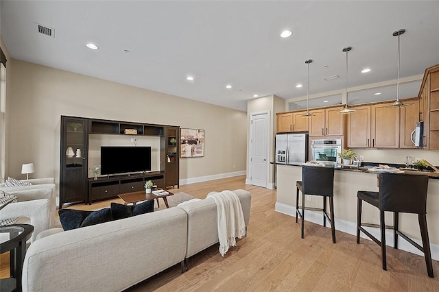 living room with light wood-type flooring, recessed lighting, and baseboards