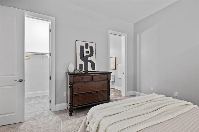 carpeted bedroom with a walk in closet, baseboards, and connected bathroom