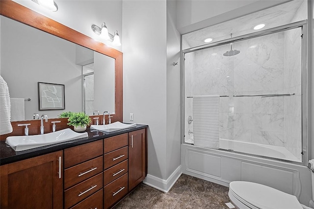 full bath featuring enclosed tub / shower combo, double vanity, toilet, and baseboards