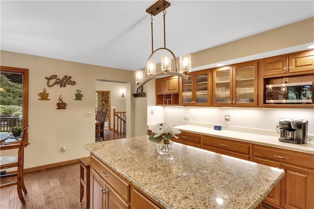 2847 National Pike, Wharton Twp, PA 15421 - kitchen featuring stainless steel microwave, brown cabinetry, a center island, glass insert cabinets, and decorative light fixtures