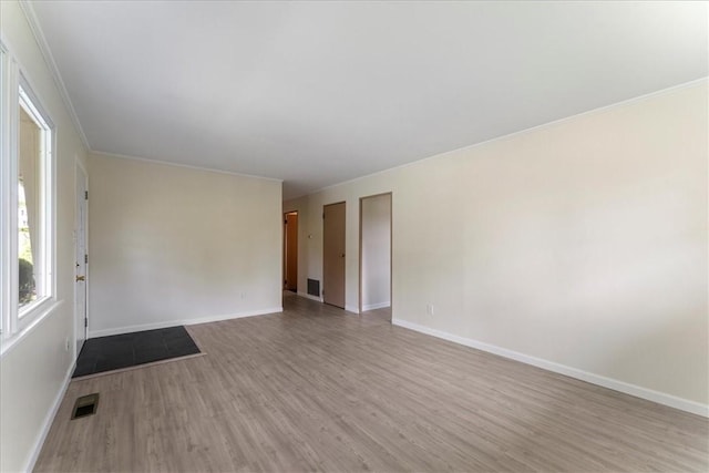 empty room featuring wood finished floors, baseboards, and ornamental molding