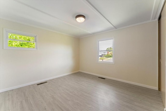 unfurnished room with light wood finished floors, baseboards, and crown molding