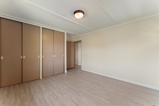 unfurnished bedroom featuring light wood-type flooring, baseboards, ornamental molding, and a closet