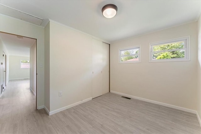 spare room with light wood-type flooring, baseboards, and ornamental molding