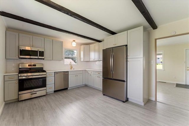 kitchen with appliances with stainless steel finishes, beam ceiling, light wood-style flooring, tasteful backsplash, and light countertops