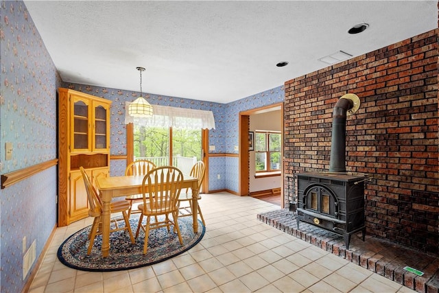 297 Alamae Lakes Rd, South Franklin, PA 15301 - dining space featuring wallpapered walls, baseboards, light tile patterned floors, a wood stove, and a textured ceiling