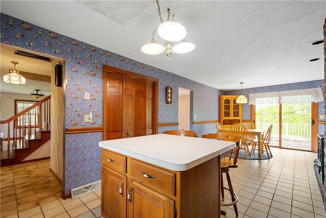 297 Alamae Lakes Rd, South Franklin, PA 15301 - kitchen with wallpapered walls, light tile patterned flooring, a center island, light countertops, and hanging light fixtures