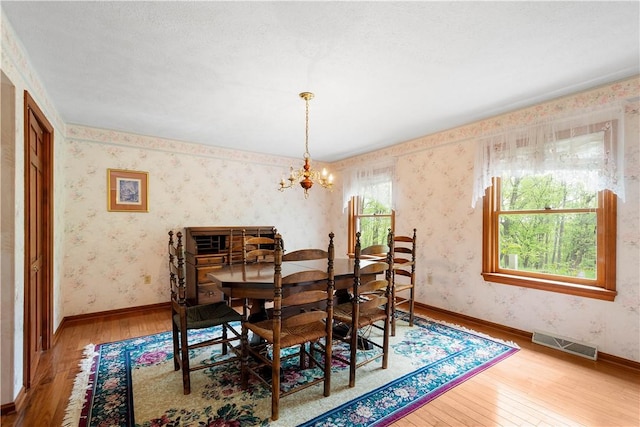 297 Alamae Lakes Rd, South Franklin, PA 15301 - dining area with hardwood / wood-style floors, a chandelier, wallpapered walls, and baseboards