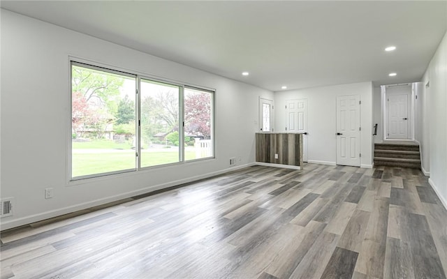 unfurnished living room featuring recessed lighting, stairs, wood finished floors, and baseboards