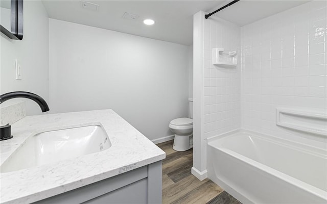 full bathroom with wood finished floors, toilet, vanity, recessed lighting, and washtub / shower combination