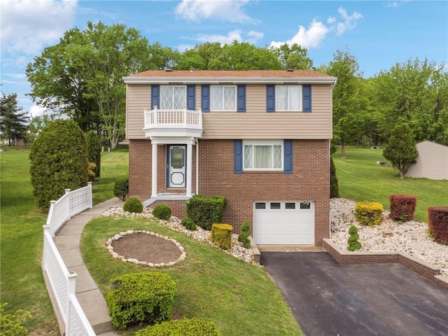 view of front of house with a garage, brick siding, asphalt driveway, a front yard, and a balcony