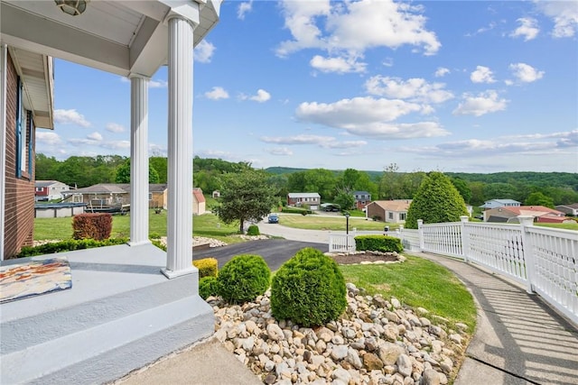 view of yard featuring covered porch, fence, and a residential view