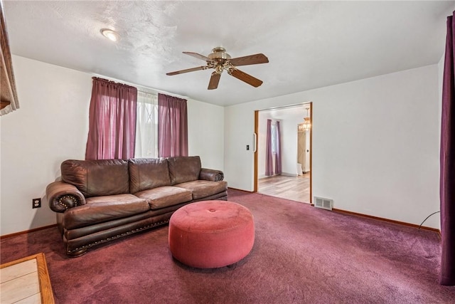 living area with ceiling fan, light carpet, and baseboards