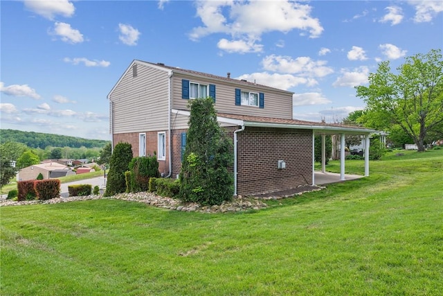 view of side of home with brick siding and a yard