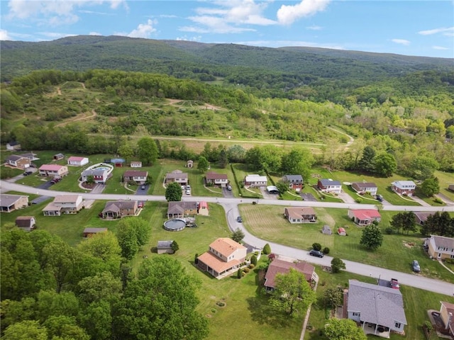 aerial view of property's location featuring a forest, nearby suburban area, and mountains